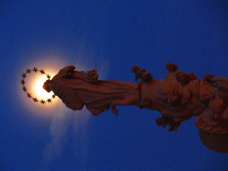 měsíc, tvořící světelnou svatozář na vrcholu Mariánského sloupu a plastiky Immaculaty